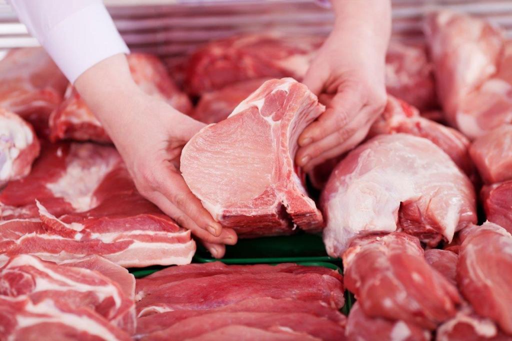 Hands picking up a fresh cut of pork. 